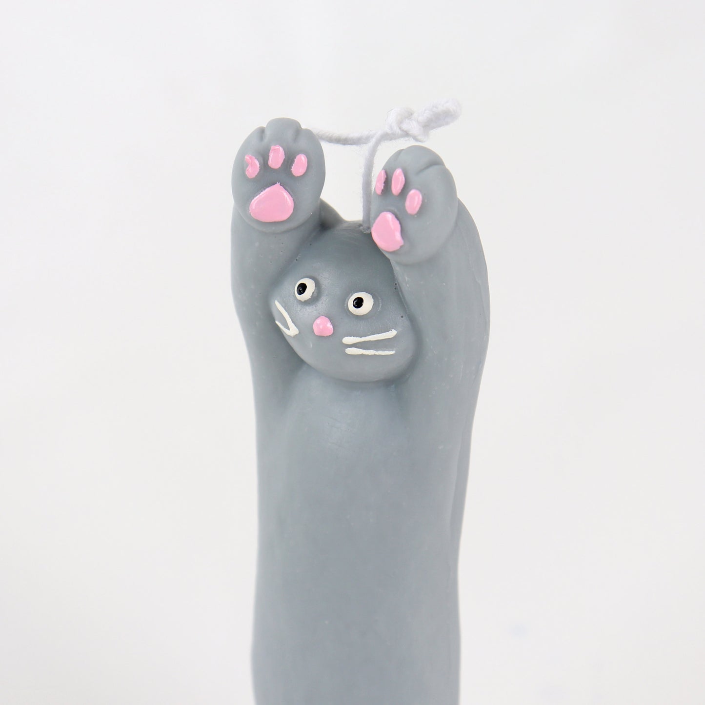 Grey candle in the shape of a cat with its paws up