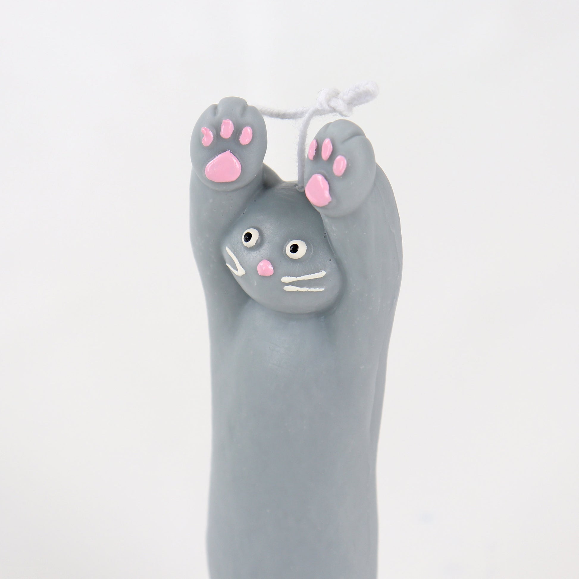 Grey candle in the shape of a cat with its paws up