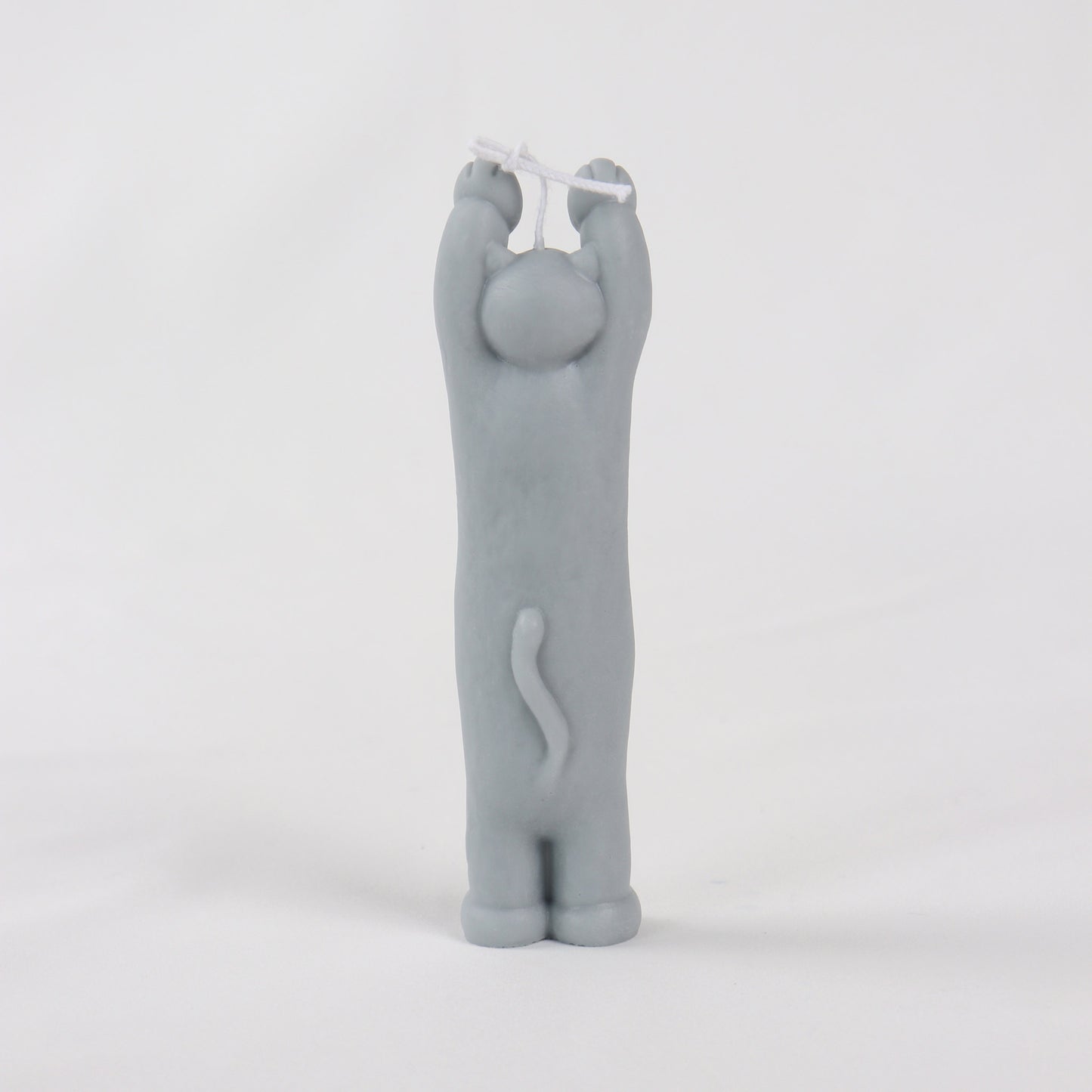Back of a grey candle in the shape of a cat standing with its paws up