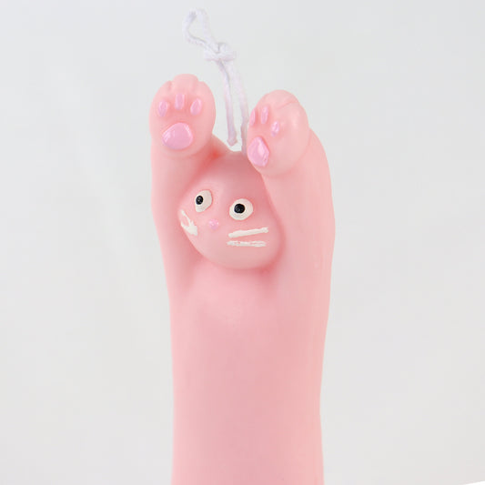 Pink candle in the shape of a cat with its paws up