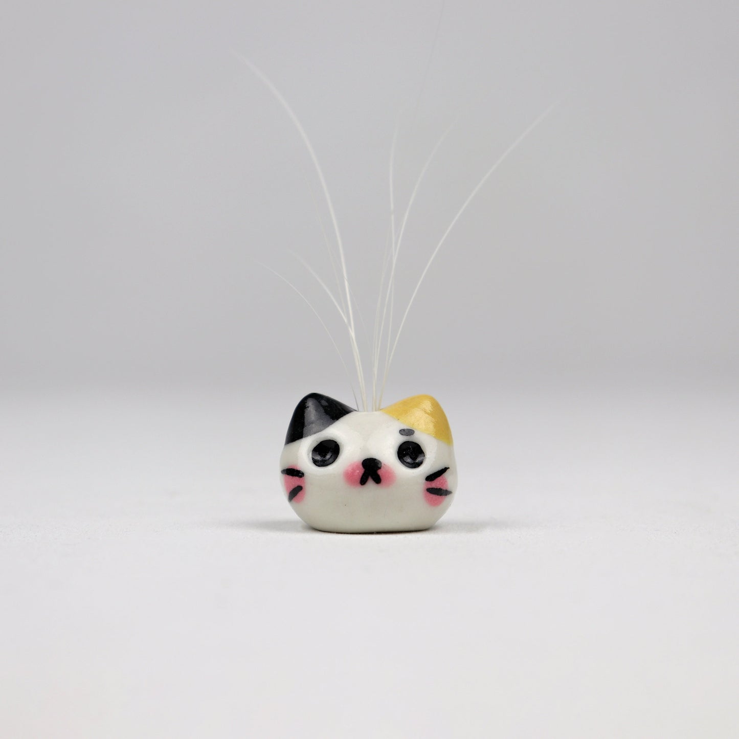 Cat shaped bud vase holding cat whiskers