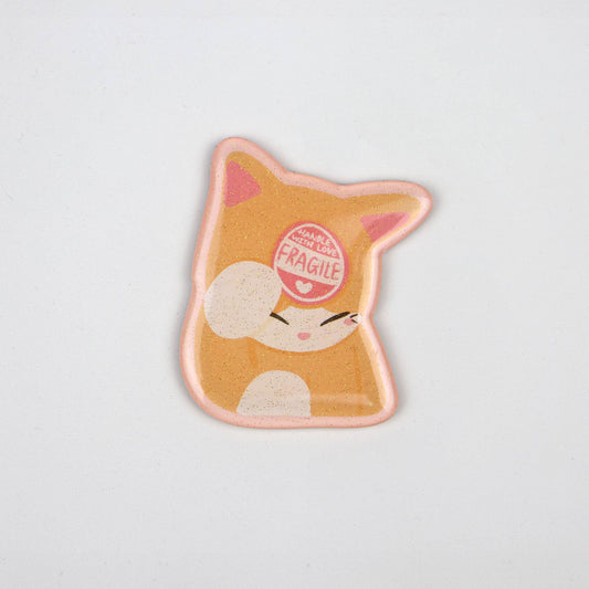 An acrylic magnet in the shape of a cat with a 'Fragile' sticker on its head.