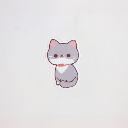 Matte die-cut waterproof sticker of a sitting grey and white cat wearing a red bowtie, approx. 5cm x 7cm.