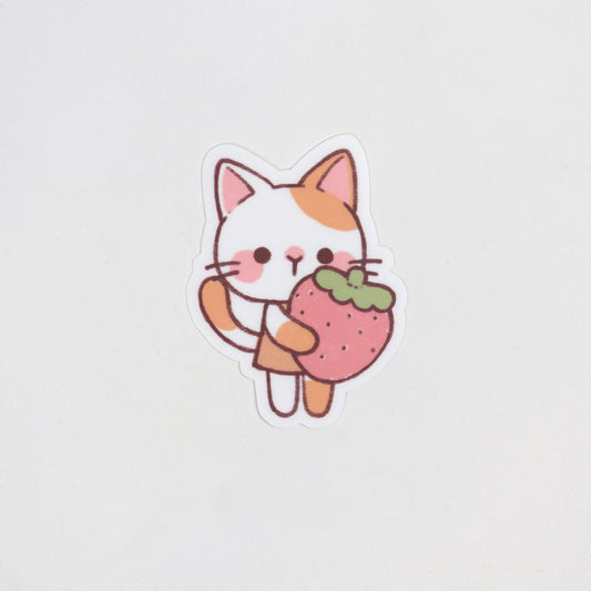 Matte waterproof sticker of a ginger and white cat standing while hugging a giant red strawberry. Die cut, approx. 5cm x 7cm.