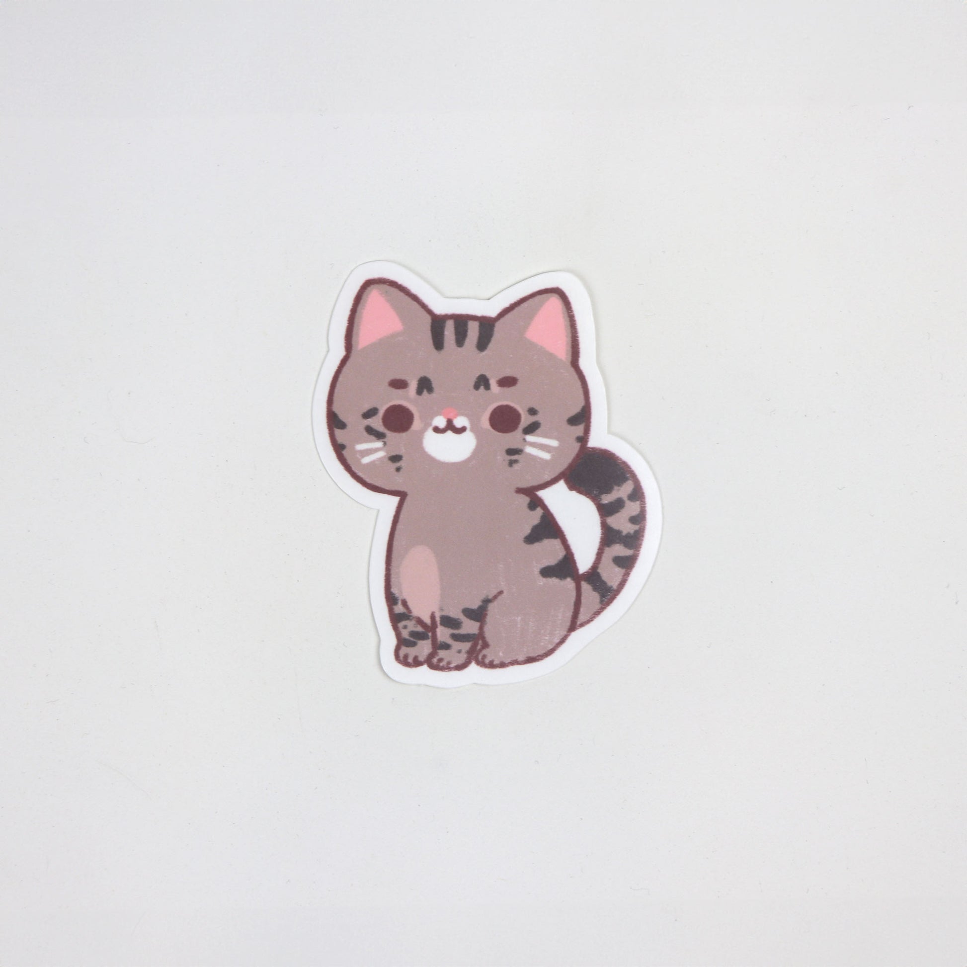 Matte die-cut waterproof sticker of a brown tabby cat with dark stripes and pink ears, approx. 5cm x 7cm.