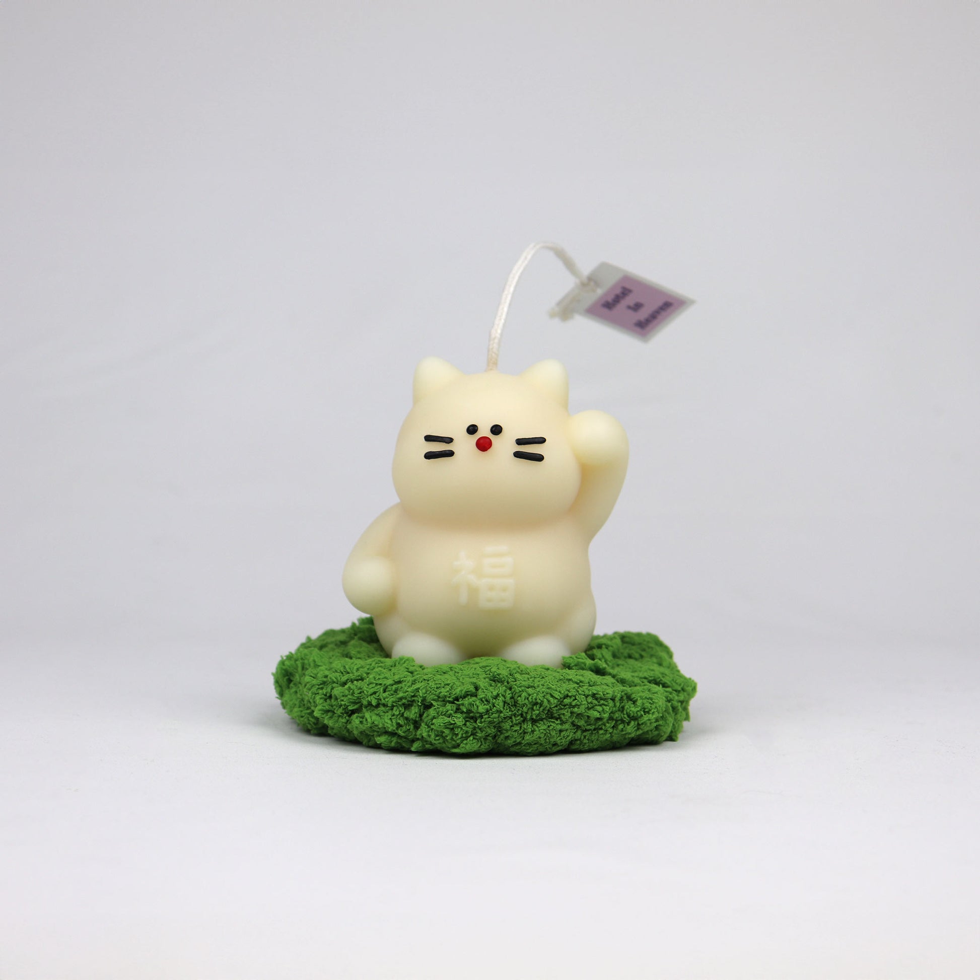 White handmade lucky cat candle with cotton wick, soy-based and scented, made in Brisbane on grass coaster