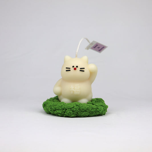 White handmade lucky cat candle with cotton wick, soy-based and scented, made in Brisbane on grass coaster