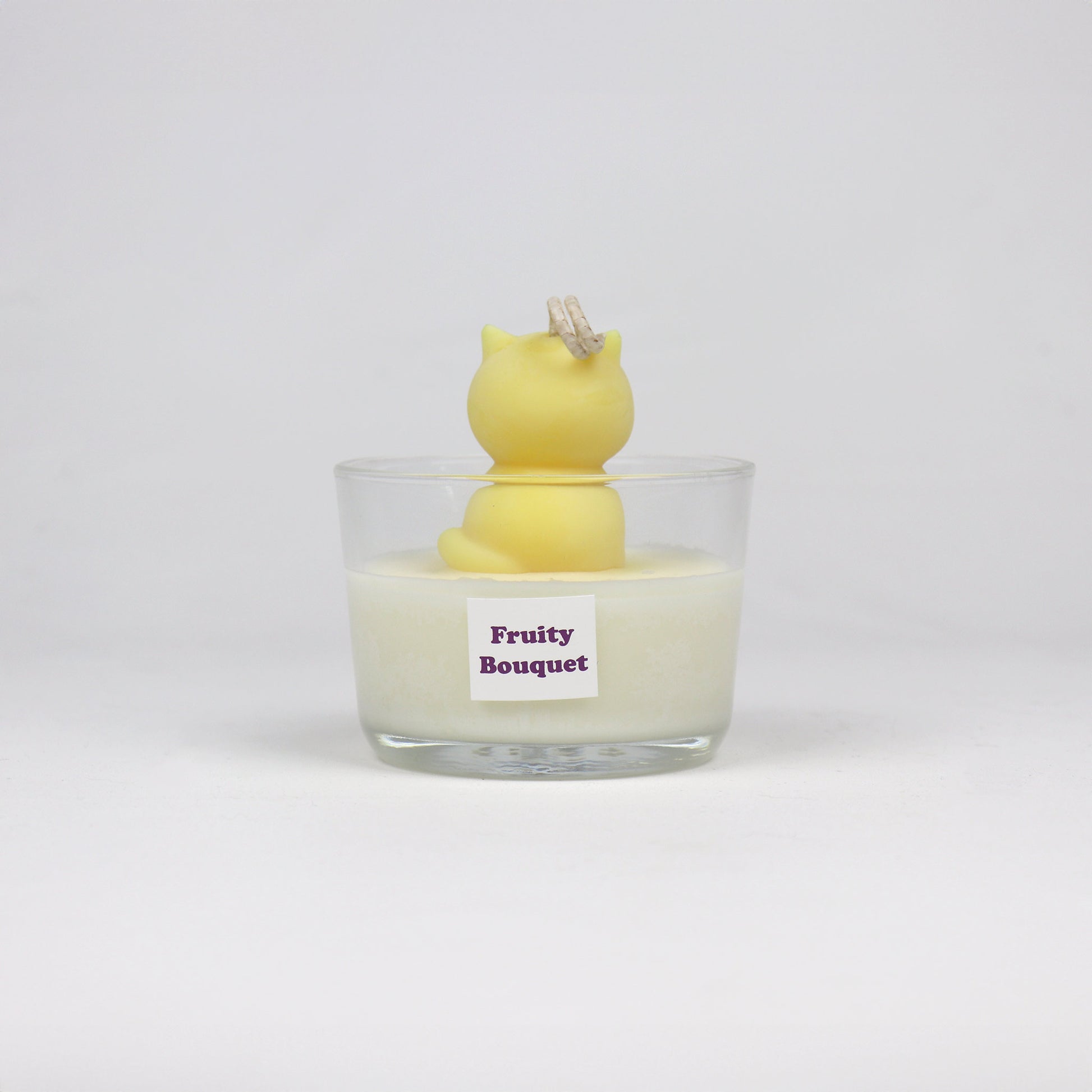 Back of yellow cat-shaped soy wax candle sitting in a glass jar, handmade in Brisbane with a cotton wick and light scent.