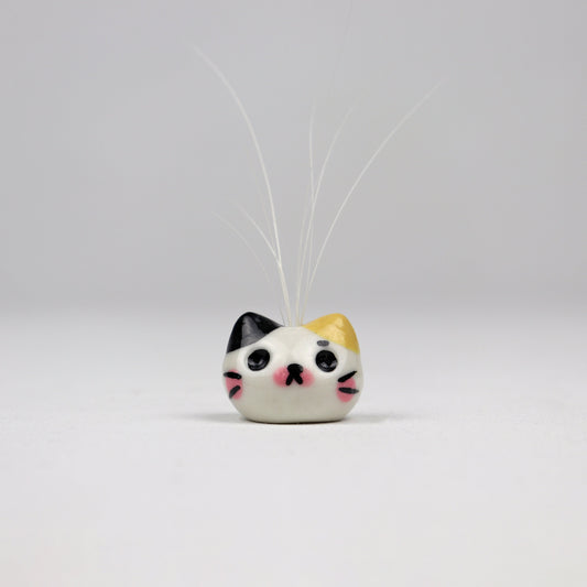 Cat shaped bud vase holding cat whiskers