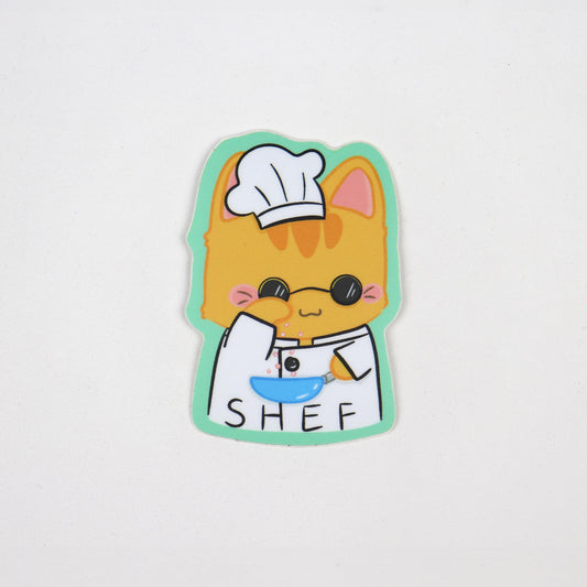 A sticker depicting a cartoon cat character dressed as a chef with a toque and an apron, holding a bowl, with the word 'SHEF' written on the apron.