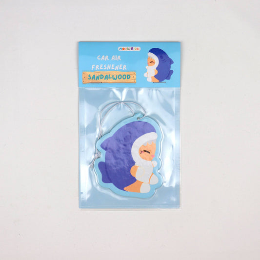 Sandalwood-scented car air freshener featuring a cute cat in a blue shark costume, illustrated by Melbourne artist duo Mouis Land. Packaged in a clear pouch with blue header card.